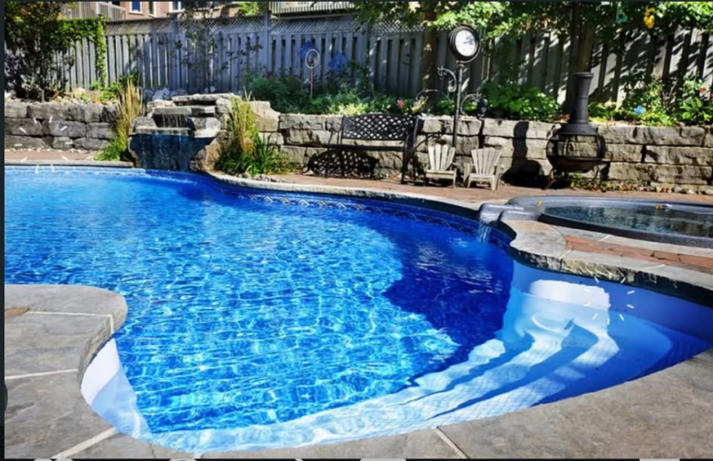 Residential pool area with spa, stone water feature, and patio furniture in Orlando, FL